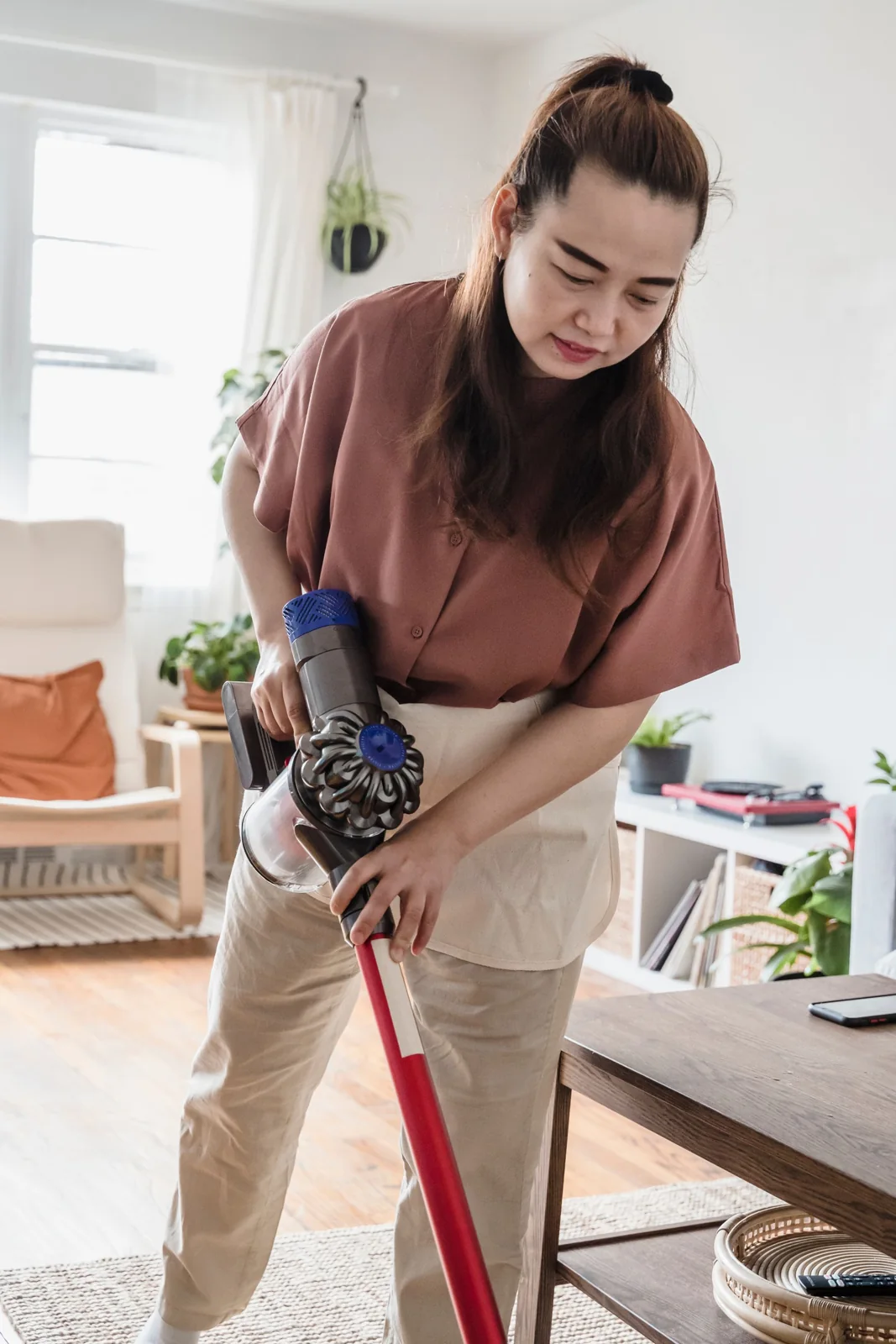 Woman vacuuming a residential living room while looking down at her work