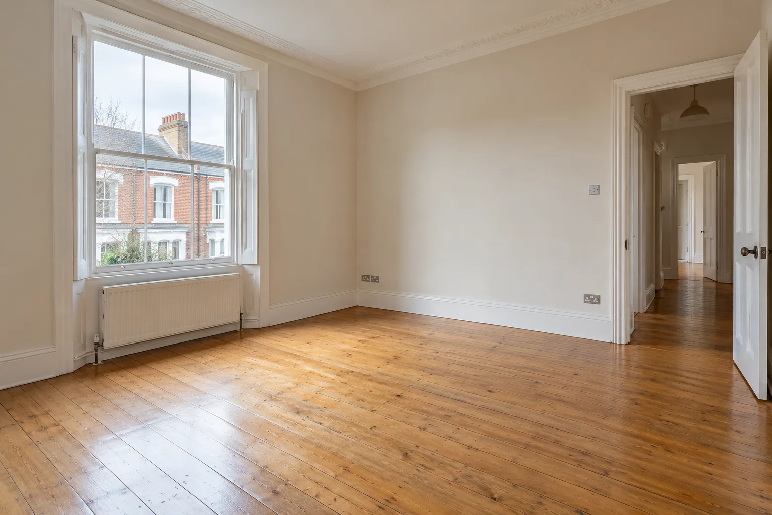 Empty British-style living room with sash windows and timber flooring (illustrative image)